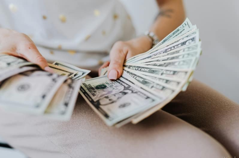 A woman confidently holds a large bundle of cash in her hands, showcasing her financial success.
