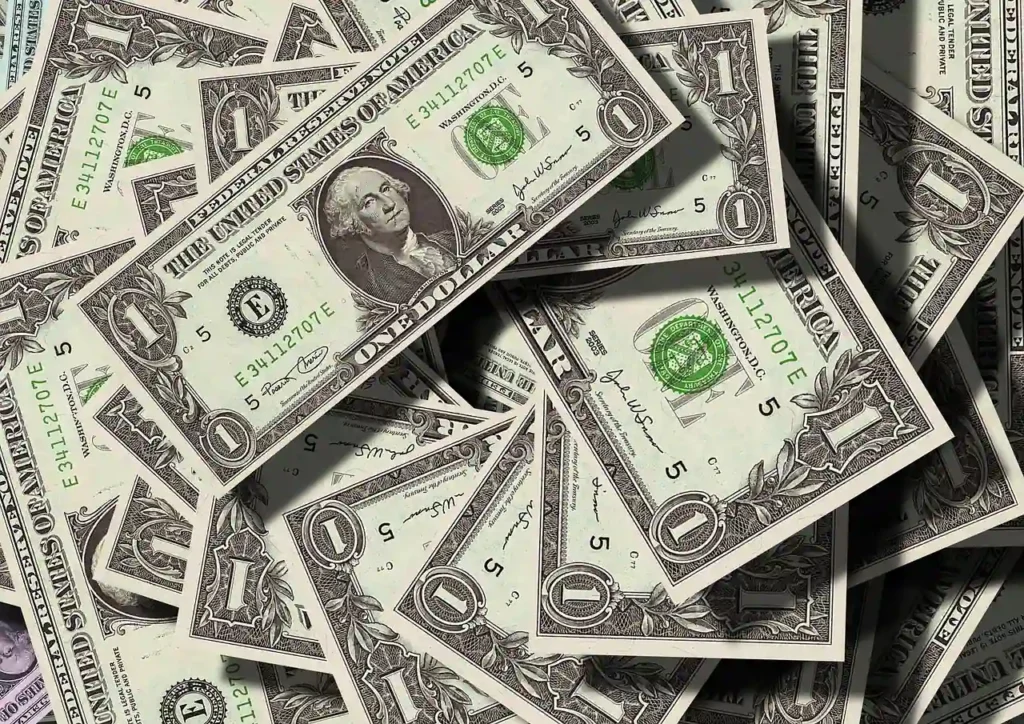 A central pile of money, consisting of various bills and coins, is prominently displayed in the image.