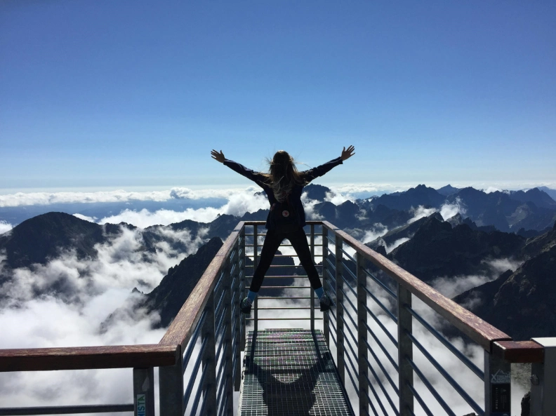A woman stands on a bridge, arms outstretched, embracing the view around her, Luxury, Billionaires, Brands, Changing the world