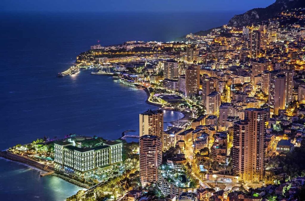 Night view of Monaco, showcasing illuminated buildings and the vibrant cityscape against a dark sky.