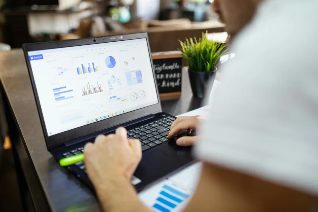 A person working on a laptop displaying various graphs and data visualizations.