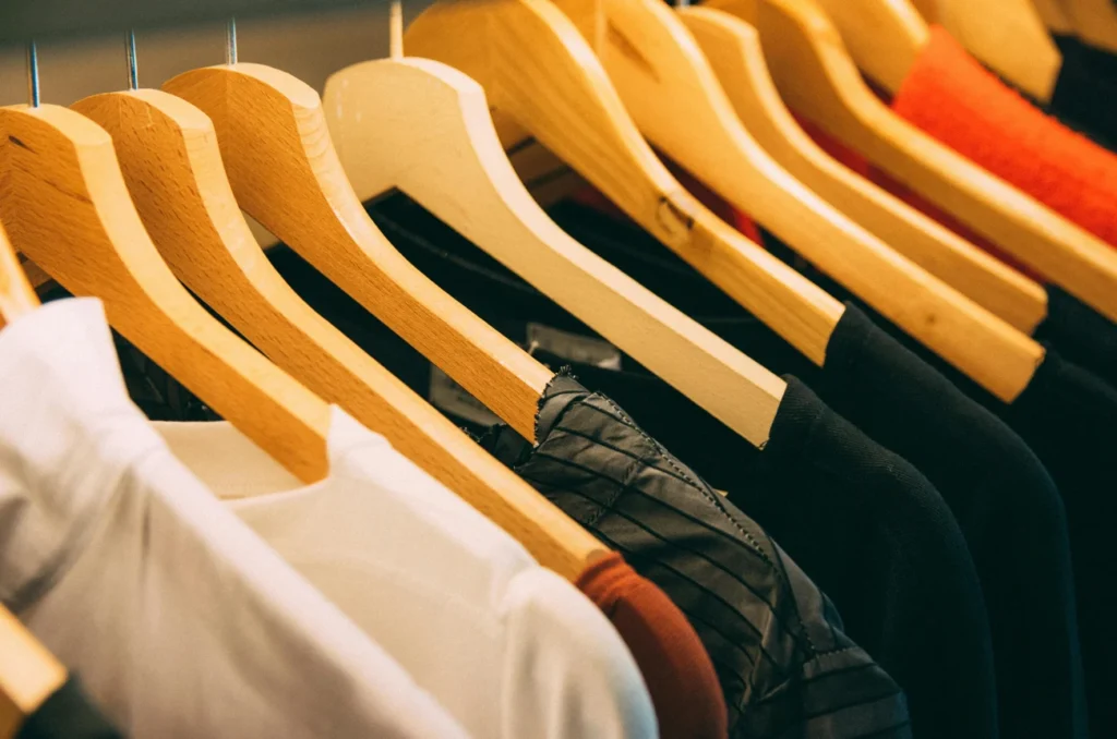 Clothes of various styles and colors hanging on hangers in a well-organized clothing store.