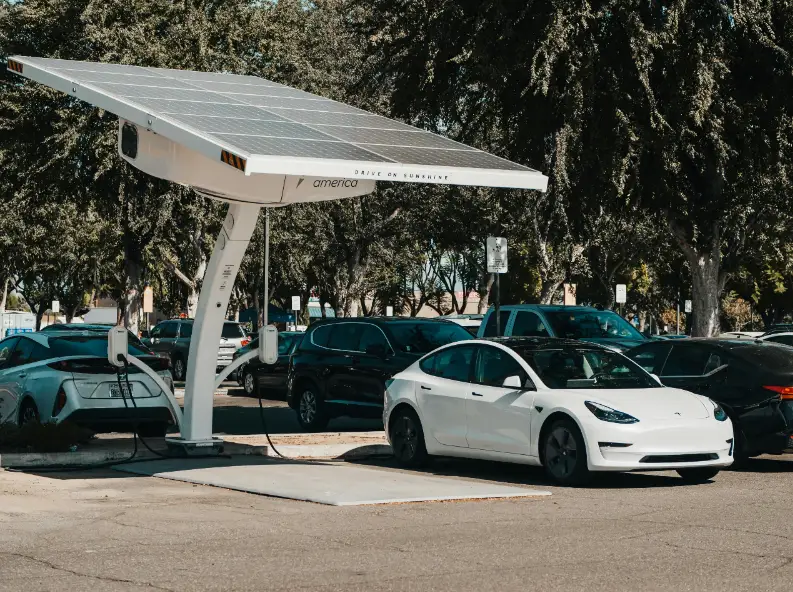  A Tesla Model 3 electric vehicle parked next to a solar panel, highlighting the integration of renewable energy and electric cars.