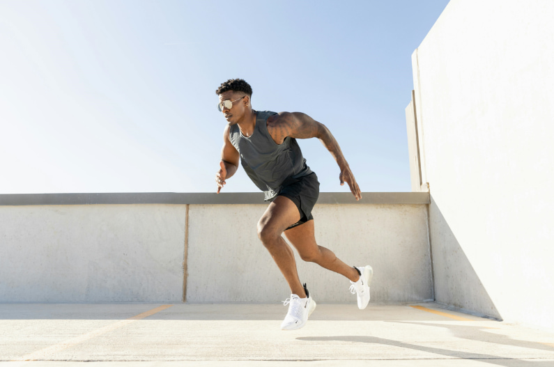 A man dressed in black is running along a vertical concrete wall, showcasing agility and strength